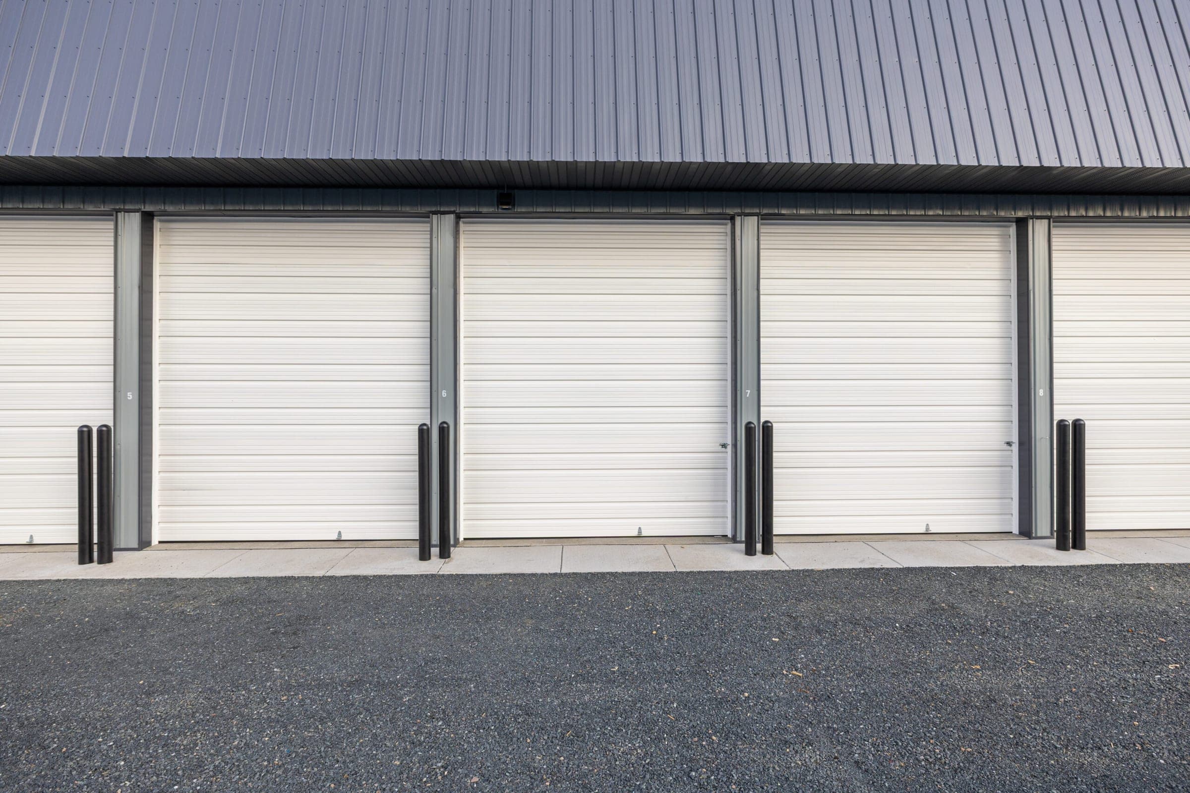 Row of drive-up storage units with white overhead doors at Precision One Storage